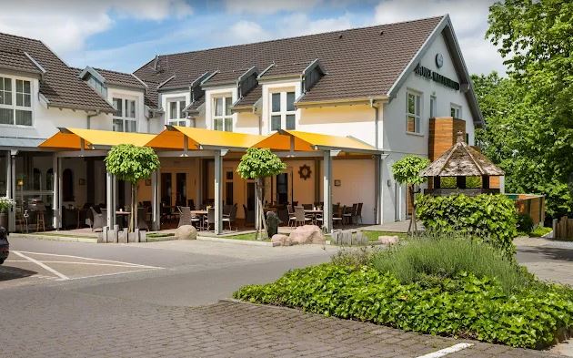 Zweistöckiges helles Gebäude mit orangefarbenem Sonnenschutz davor Foto der Außenstelle Herford, Hotel Waldesrand