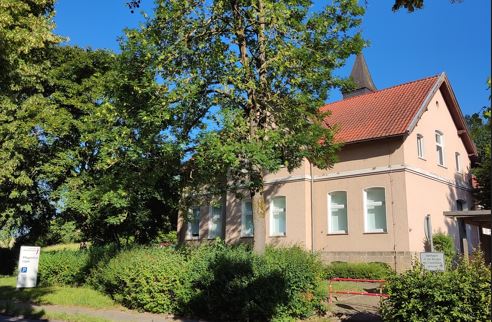Cremefarbendes Haus mit hohen Fenstern und Glockenturm im Hintergrund Foto der Außenstelle Blomberg, Pflegeschule Lippe