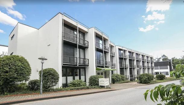 Langgezogener weißer Flachbau mit drei Stockwerken und Balkonen Foto der Außenstelle Bielefeld/Senne, Haus Neuland